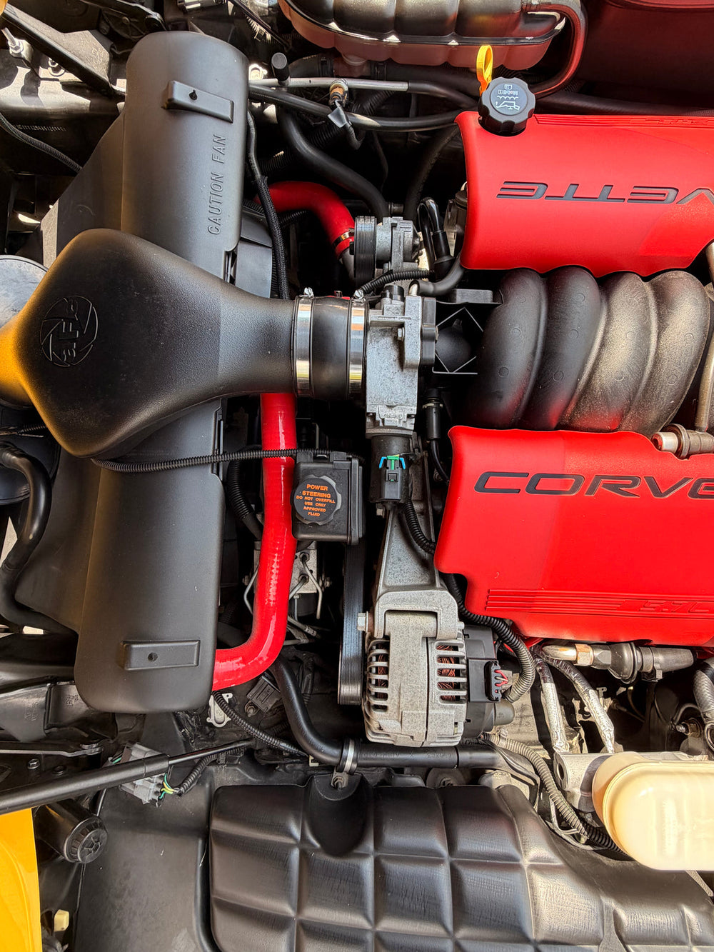 Engine-bay detail of Justin Todd’s yellow Corvette with red Corvette covers.