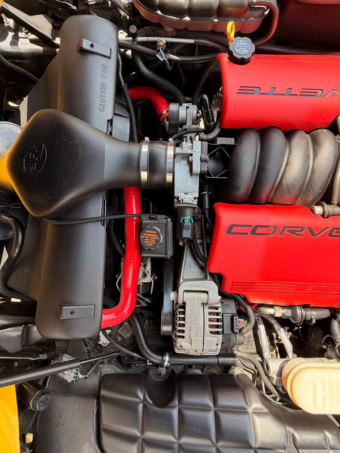 Engine-bay detail of Justin Todd’s yellow Corvette with red Corvette covers.